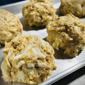 Crab cakes on a metal baking tray.